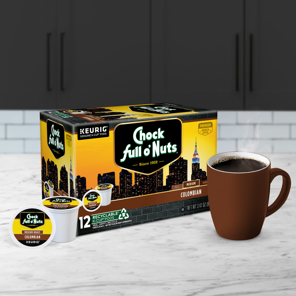 A box of Chock full o'Nuts Colombian - Keurig K-Cup® Pods - Medium Roast sits next to a filled brown mug on a kitchen counter, offering the rich taste of 100% Arabica coffee beans.