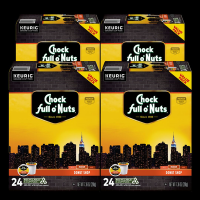 Four boxes of Chock full o'Nuts Donut Shop - Keurig K-Cup Pods - Medium Roast, each with 24 pods of premium Arabica coffee beans, are displayed against a city skyline featuring the Empire State Building, encapsulating the vibrant energy of New York City.