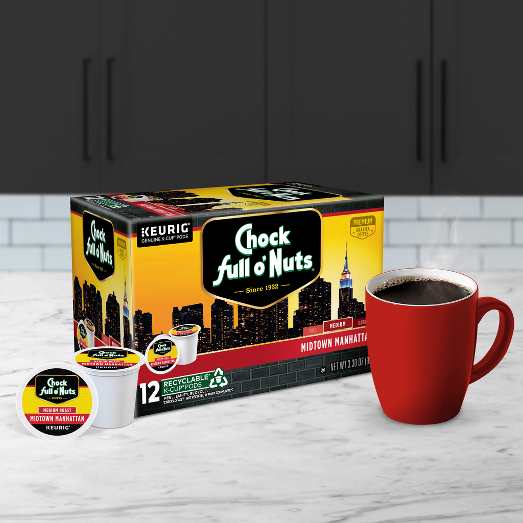 A box of Chock full o'Nuts Midtown Manhattan - Keurig K-Cup® Pods - Medium Roast is on the kitchen countertop, beside a red mug filled with premium Arabica coffee.