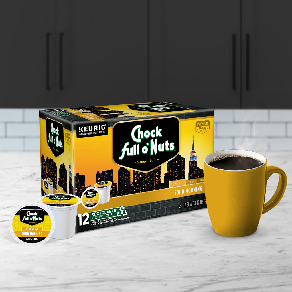 A box of Chock full o'Nuts Soho Morning - Keurig K-Cup® Pods - Mild Roast is placed on a counter next to a yellow mug brimming with rich, aromatic coffee.