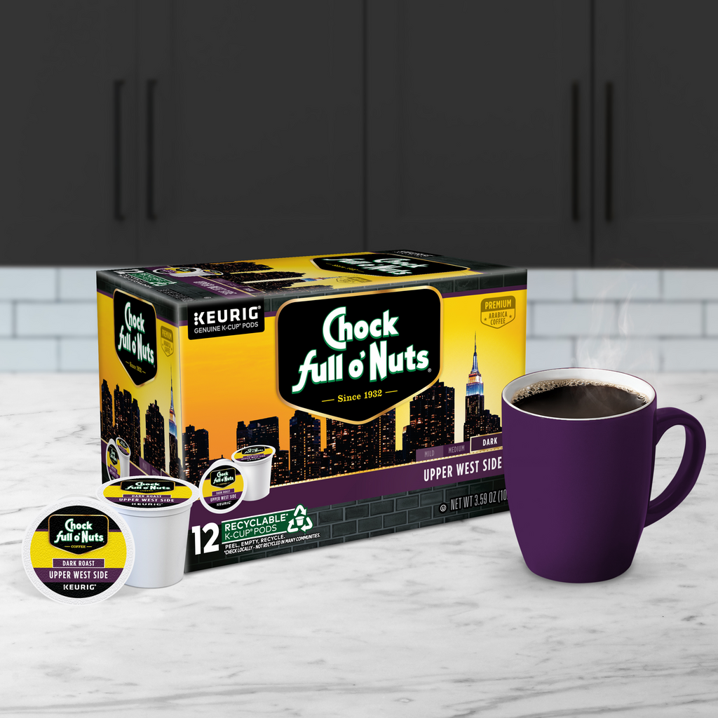 A box of Chock full o'Nuts Upper West Side - Keurig K-Cup® Pods - Dark Roast is placed next to a purple mug of premium Arabica coffee on a kitchen counter.