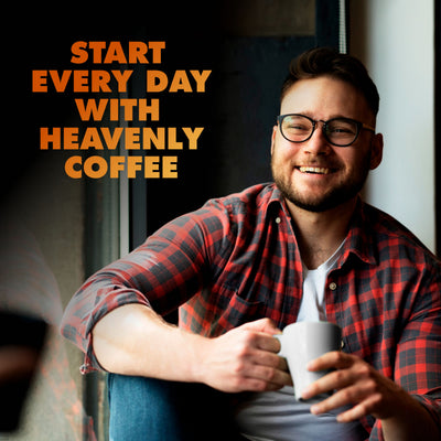 A man in glasses and a plaid shirt smiles by a window, holding a white mug. Text reads, "Begin your day with Chock full o’Nuts Donut Shop K-Cup® Pods—premium medium roast Arabica coffee.